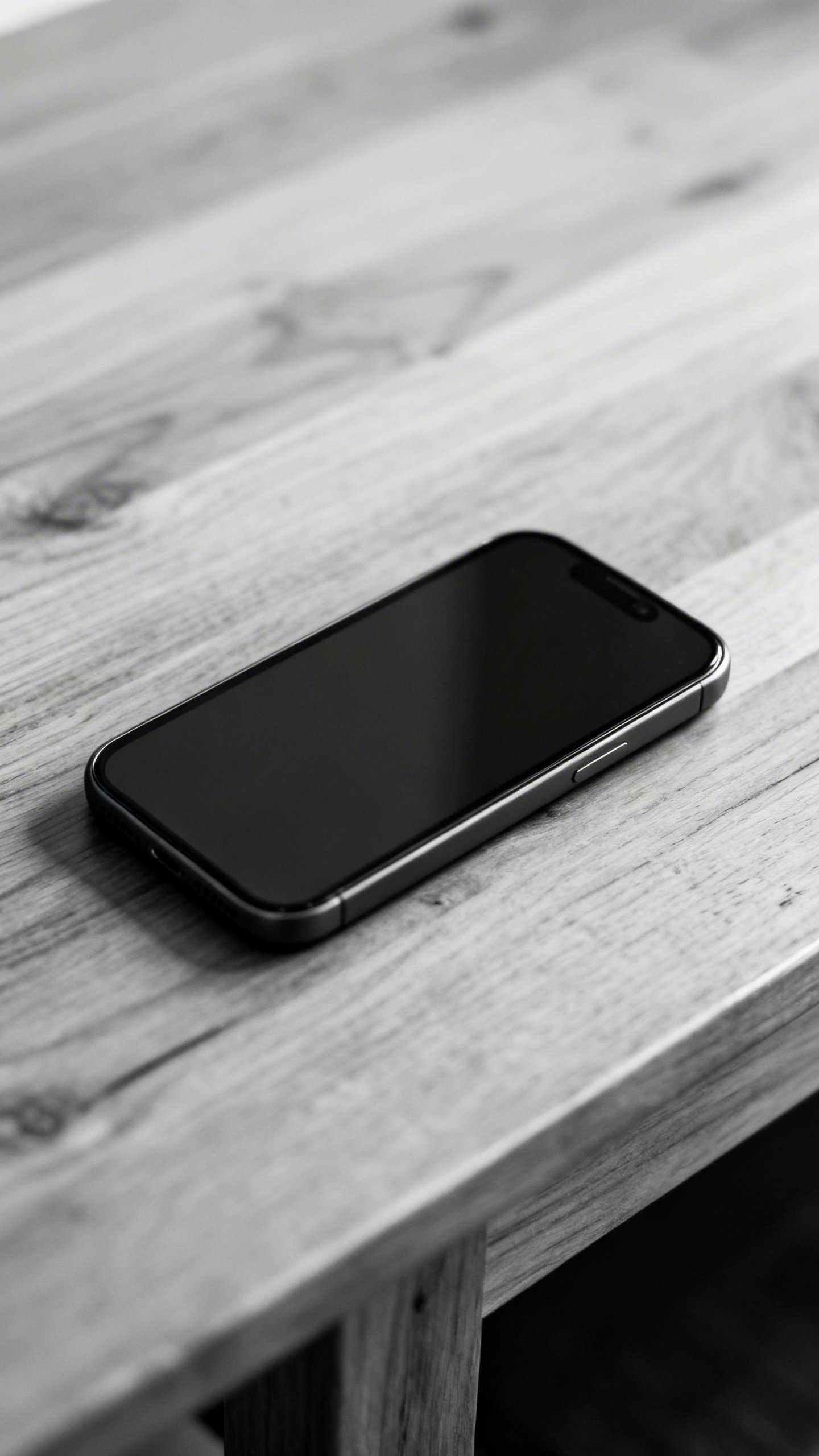 Closeup of grayscale smartphone on wooden table, notifications off